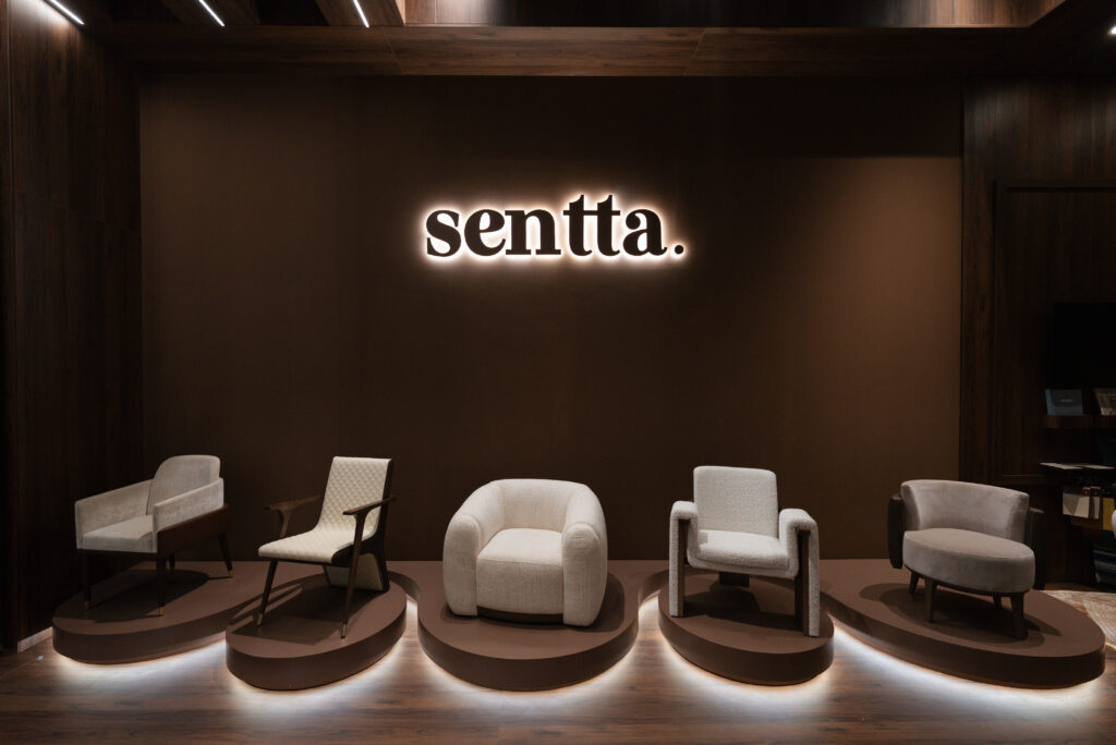 The cénic atmosphere of the Sentta stand at Salone del Mobile 2026, featuring the new Vellure, Floow, Avoria, and Kado armchairs during the exclusive April 23 event.